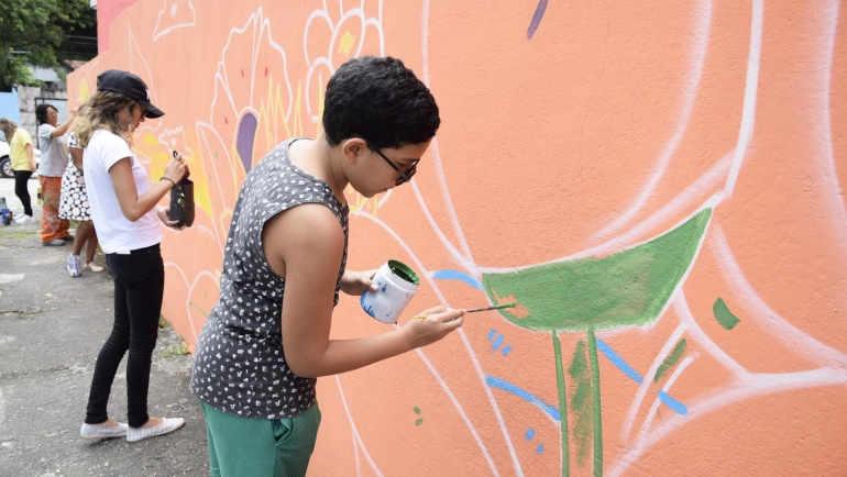 Mulheres pintam o desenho de um muro, em ação do Mais Vida nos Morros